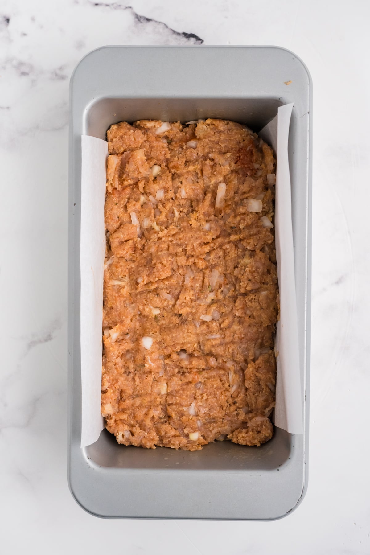 Meatloaf mixture in a prepared loaf pan.