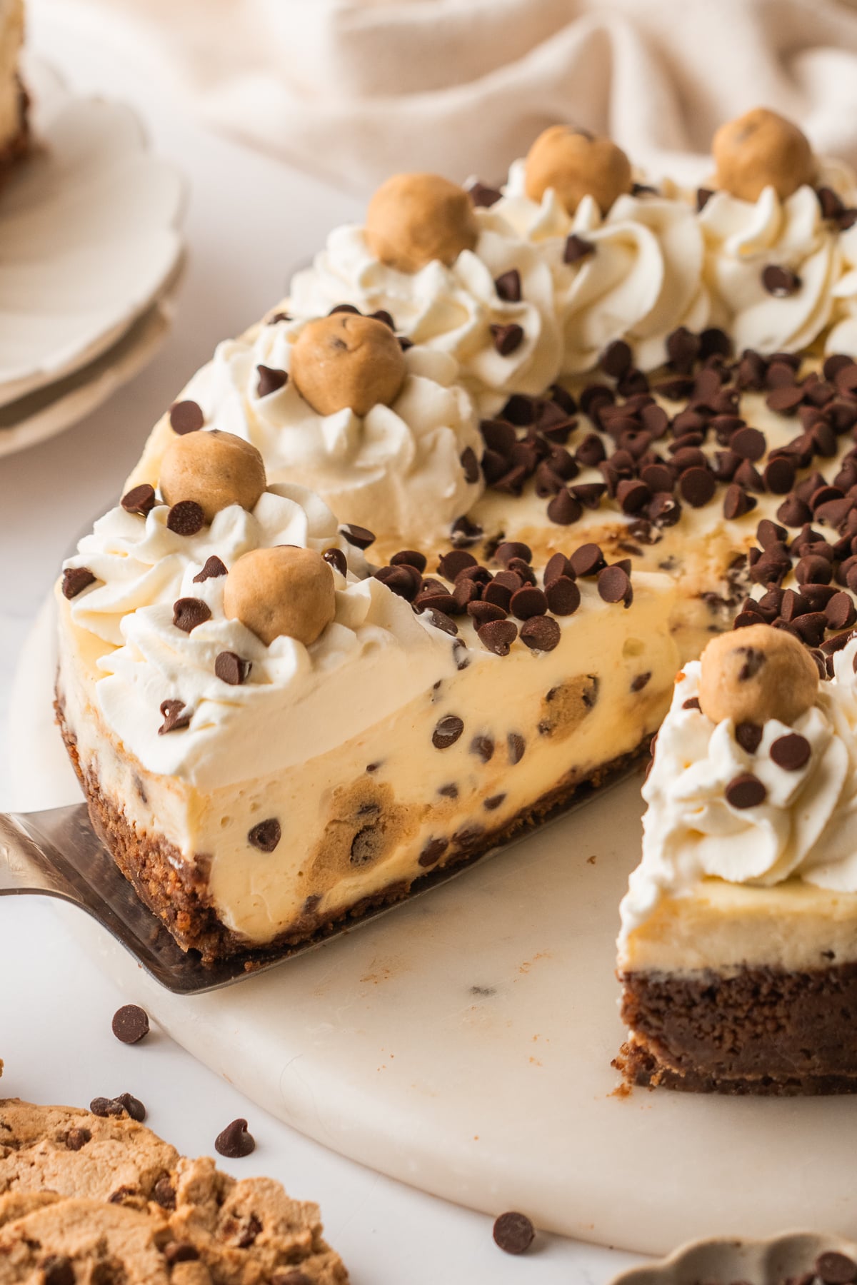 A slice of cookie dough cheesecake being scooped up by a spatula.