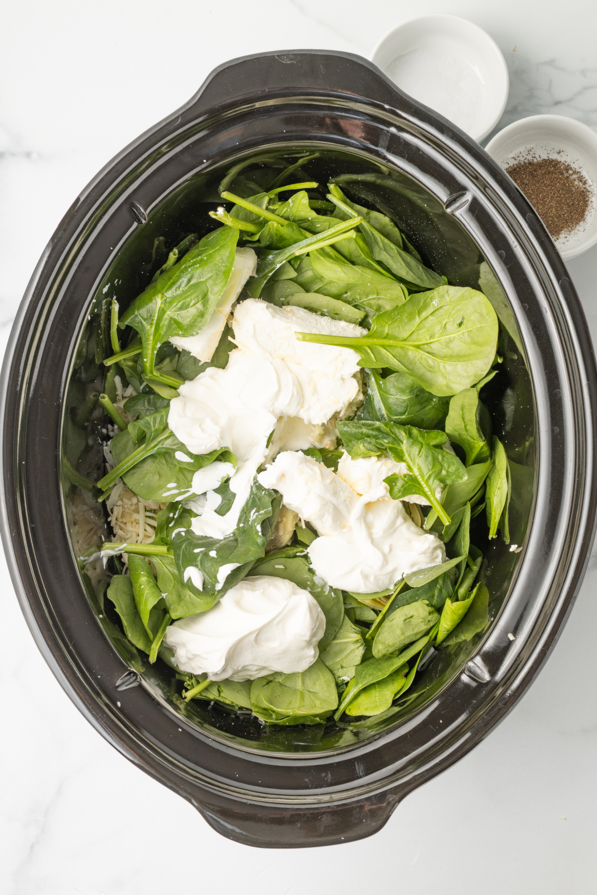 All the ingredients for the spinach artichoke dip into the bottom of the crockpot.