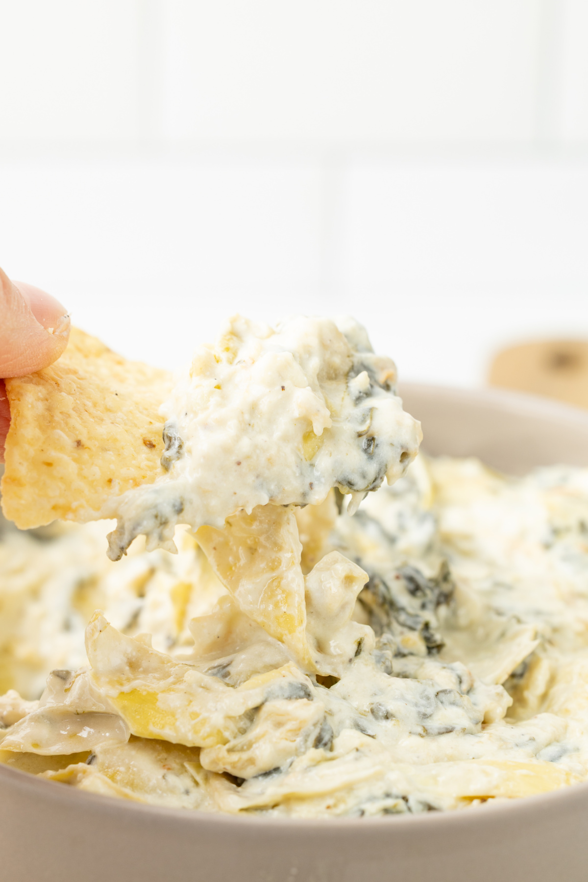 A chip scooping up some spinach artichoke dip.