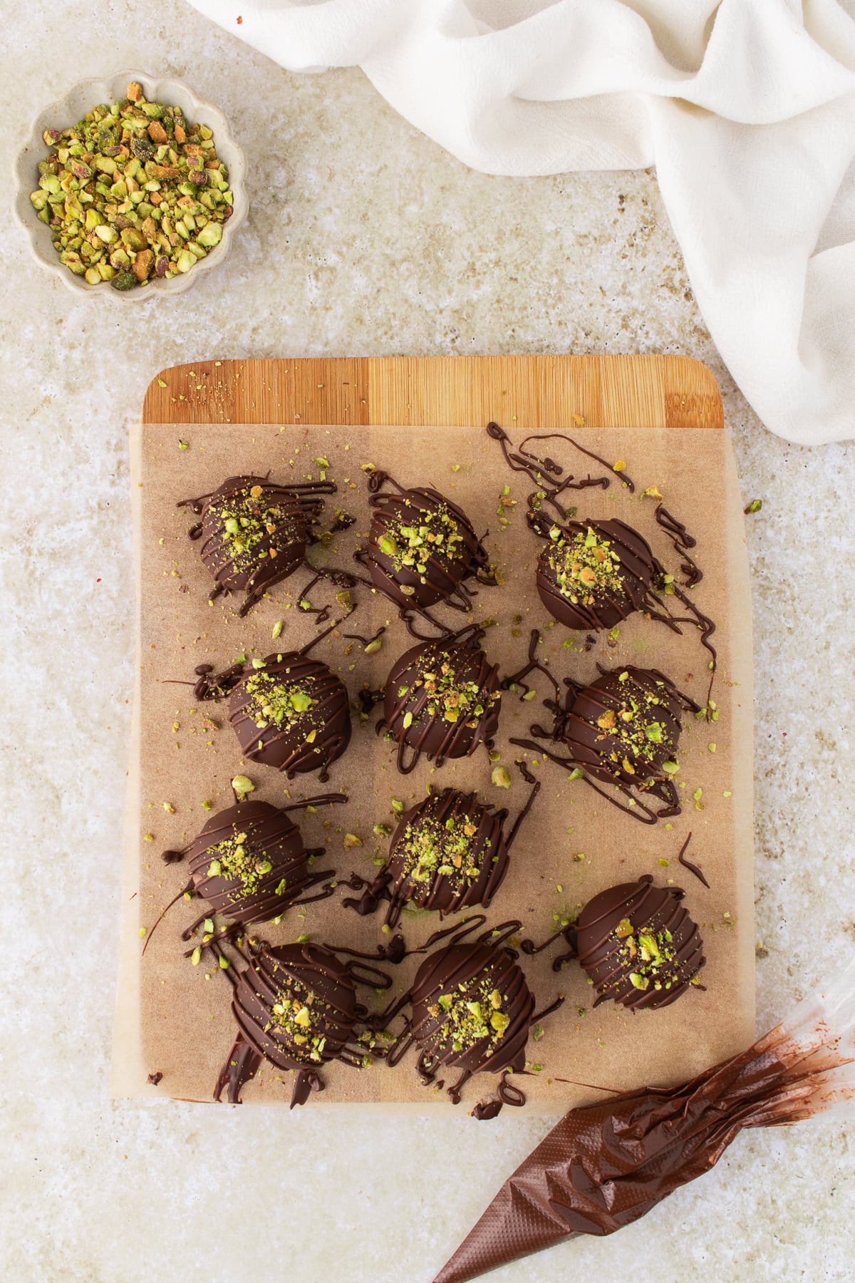 Crushed pistachios and chocolate drizzled on top of the formed truffle.