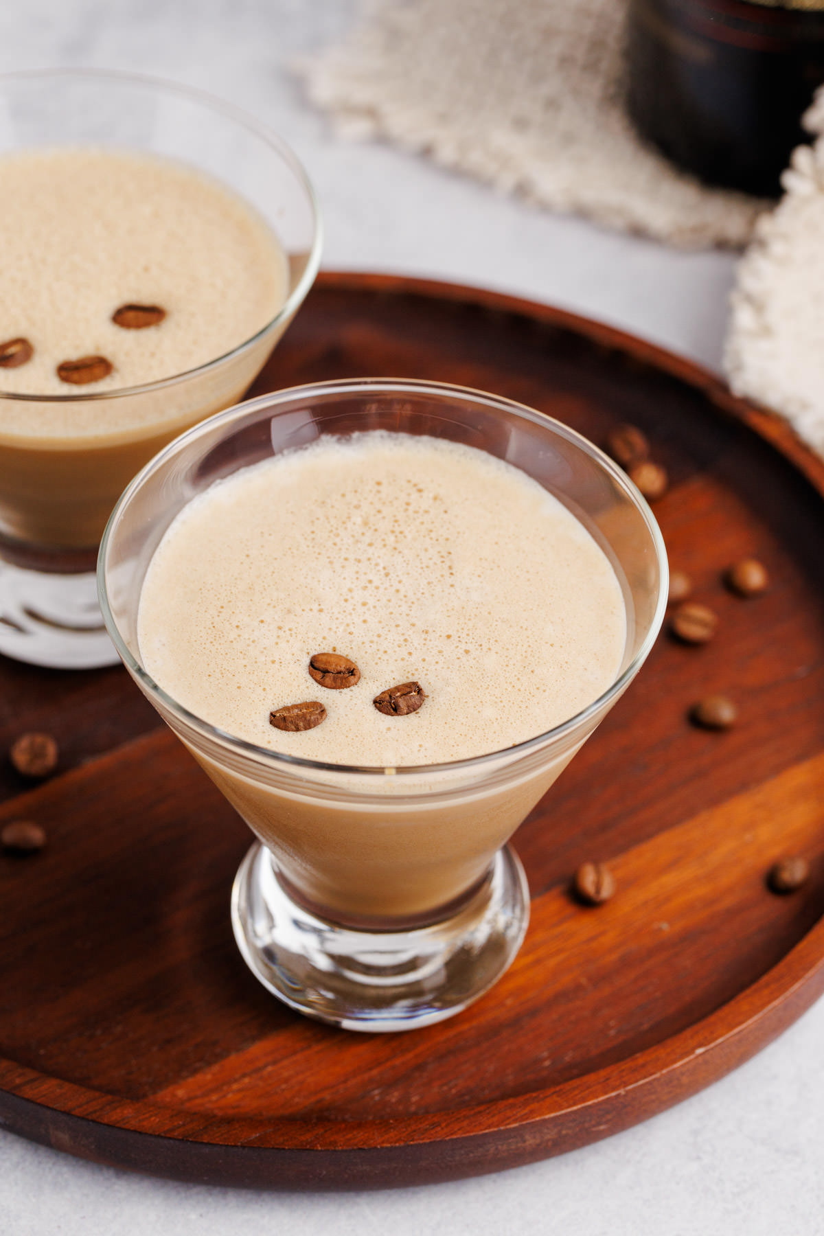 A glass filled with espresso martini and coffee beans on top.