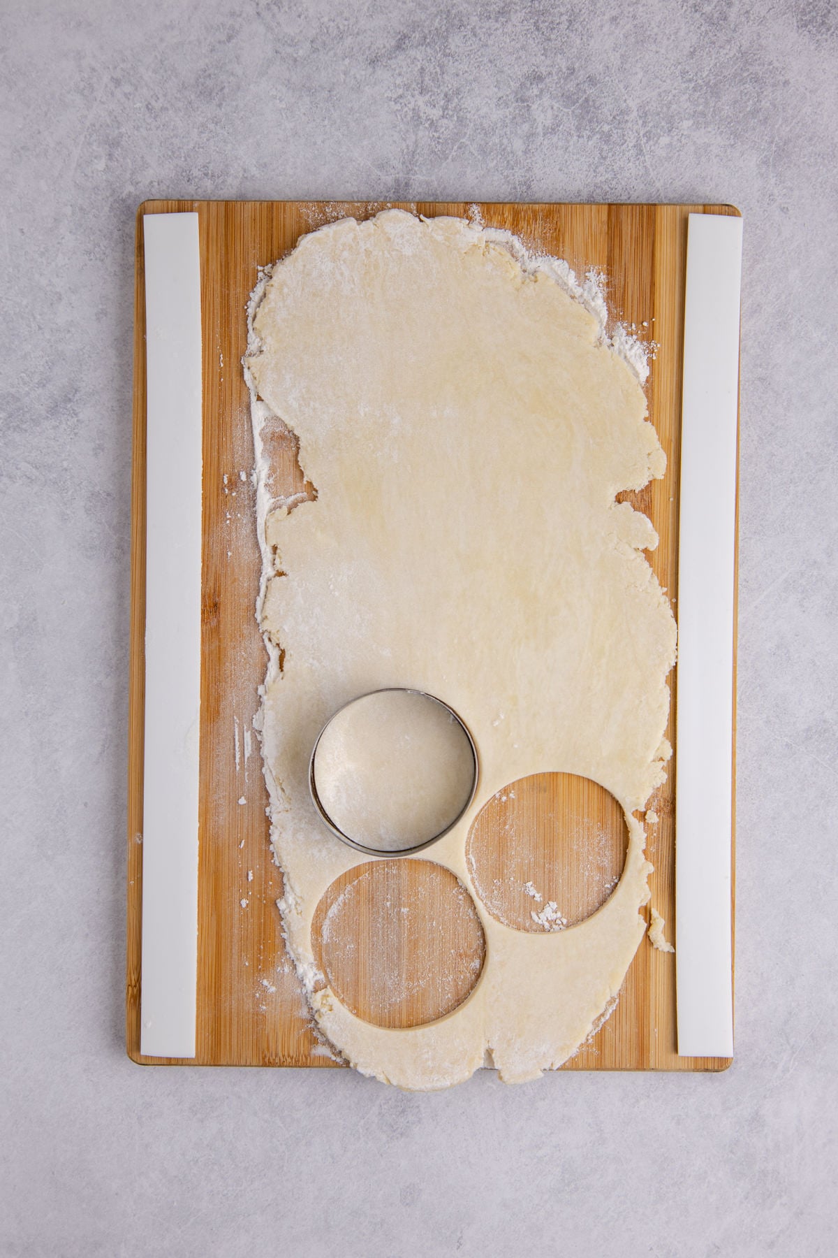 Rolled out dough on cutting board with three rounds cut.
