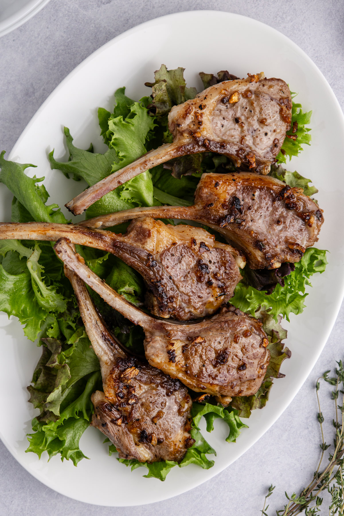 A plate of skillet lamb chops over lettuce.