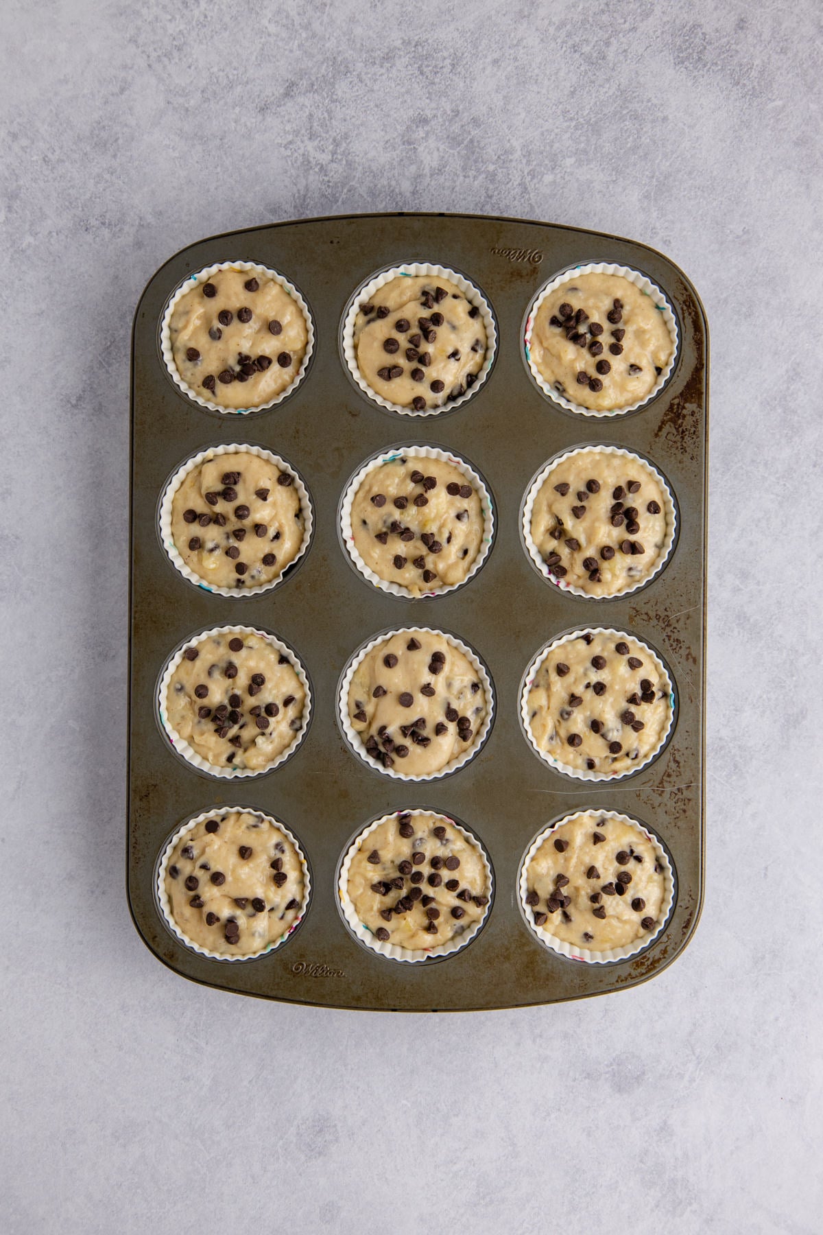 The muffin batter scooped into the muffin pan.