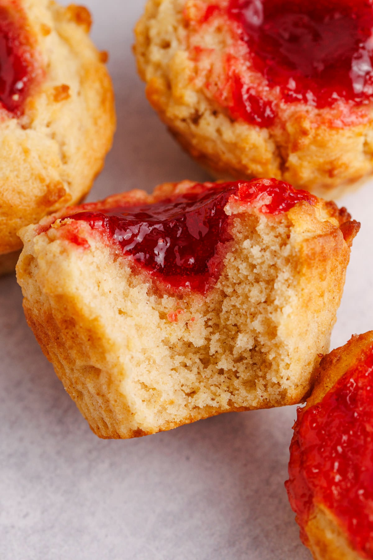 A PBJ muffin with a bite taken out of it exposing the jelly in the center.