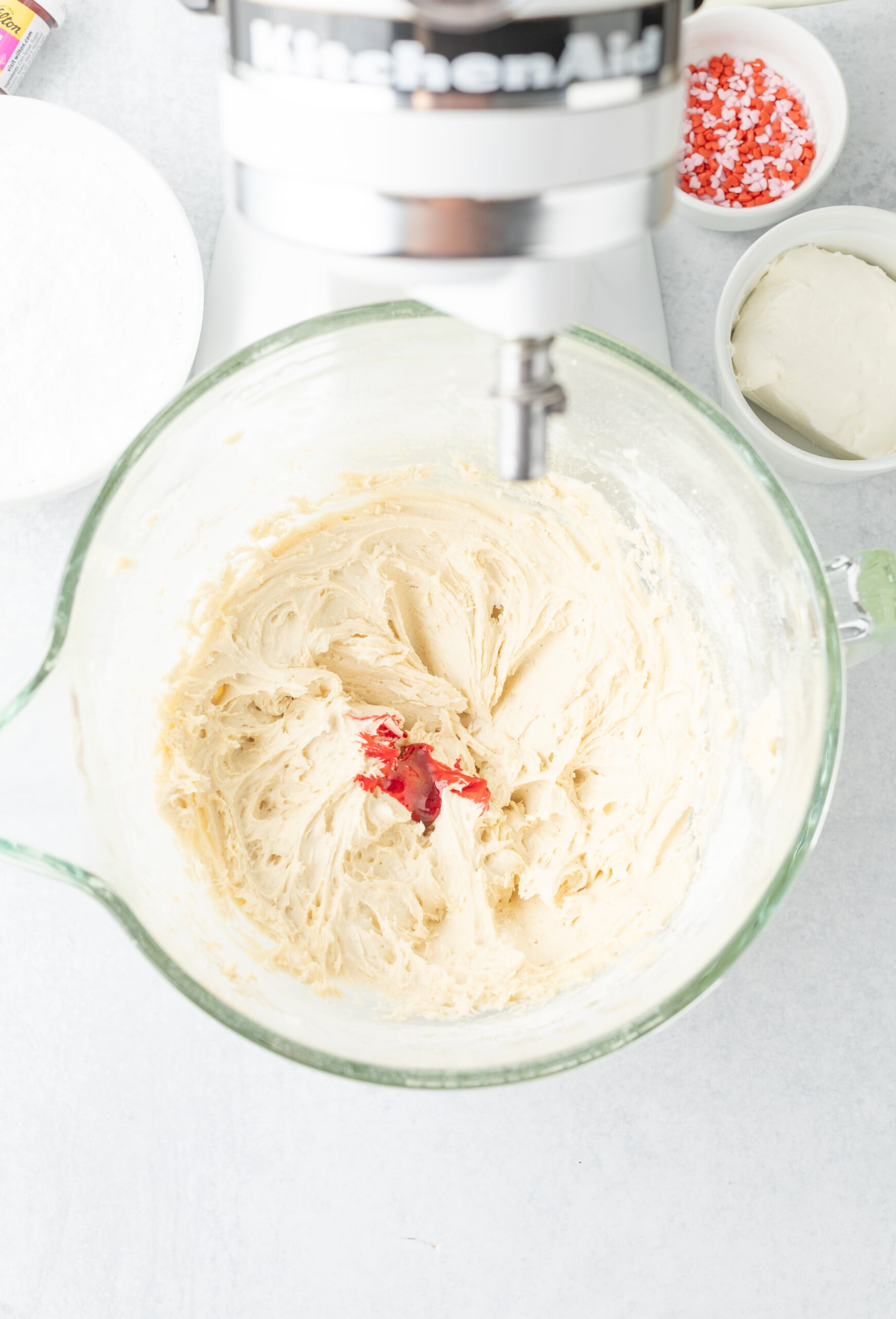 Butter, sugar, vanilla, egg and pink food coloring beaten in a bowl.