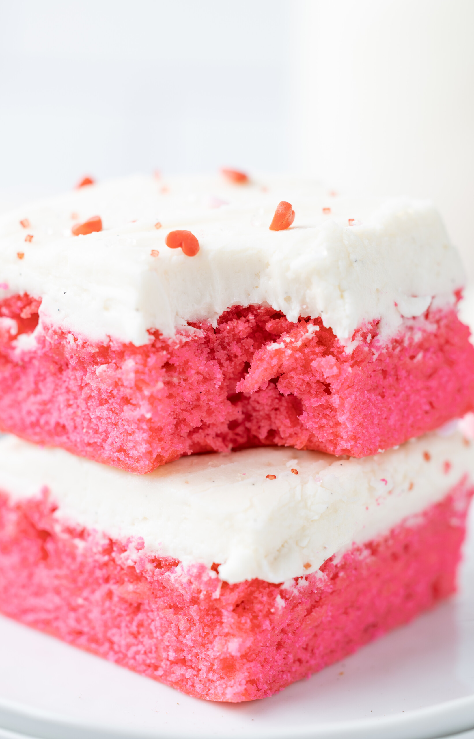 A pink brownie with a bite taken out of it on top of another brownie.
