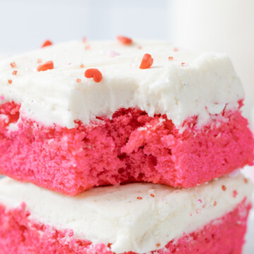 A pink velvet brownie on a table with a bite out of it.