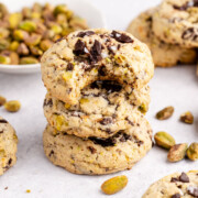 Pistachio chocolate chip cookies stacked with the top cookie bitten.