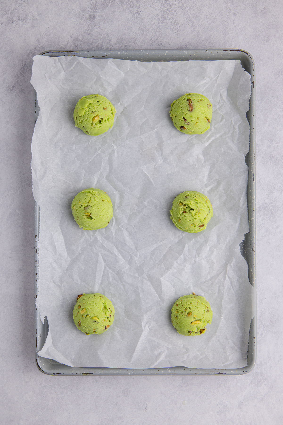 Cookie dough scooped into balls on a sheet pan.