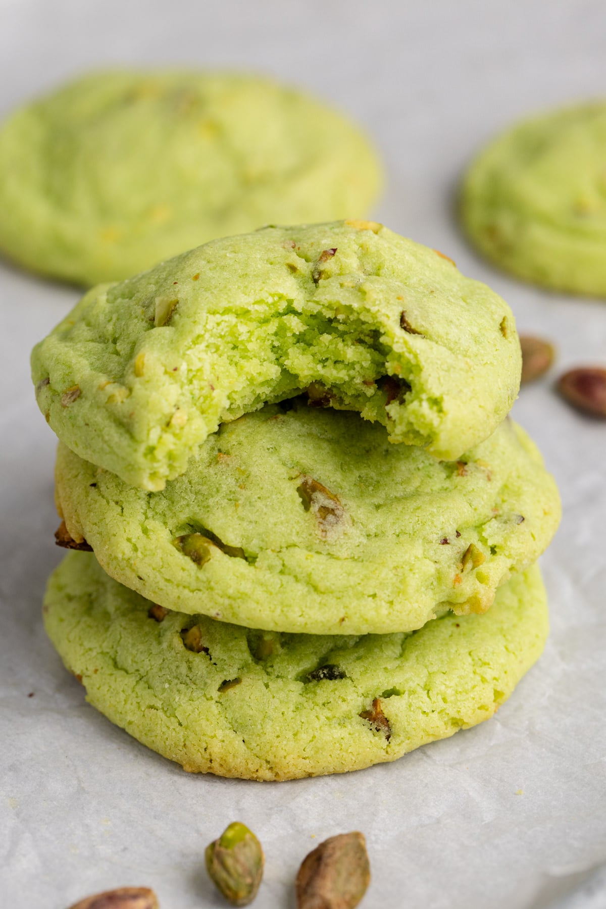 A stack on cookies with pistachios with a bite taken out of the cookie.