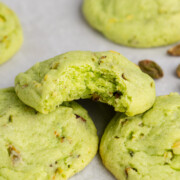 Pistachio pudding cookies with a bite taken out of the cookie.