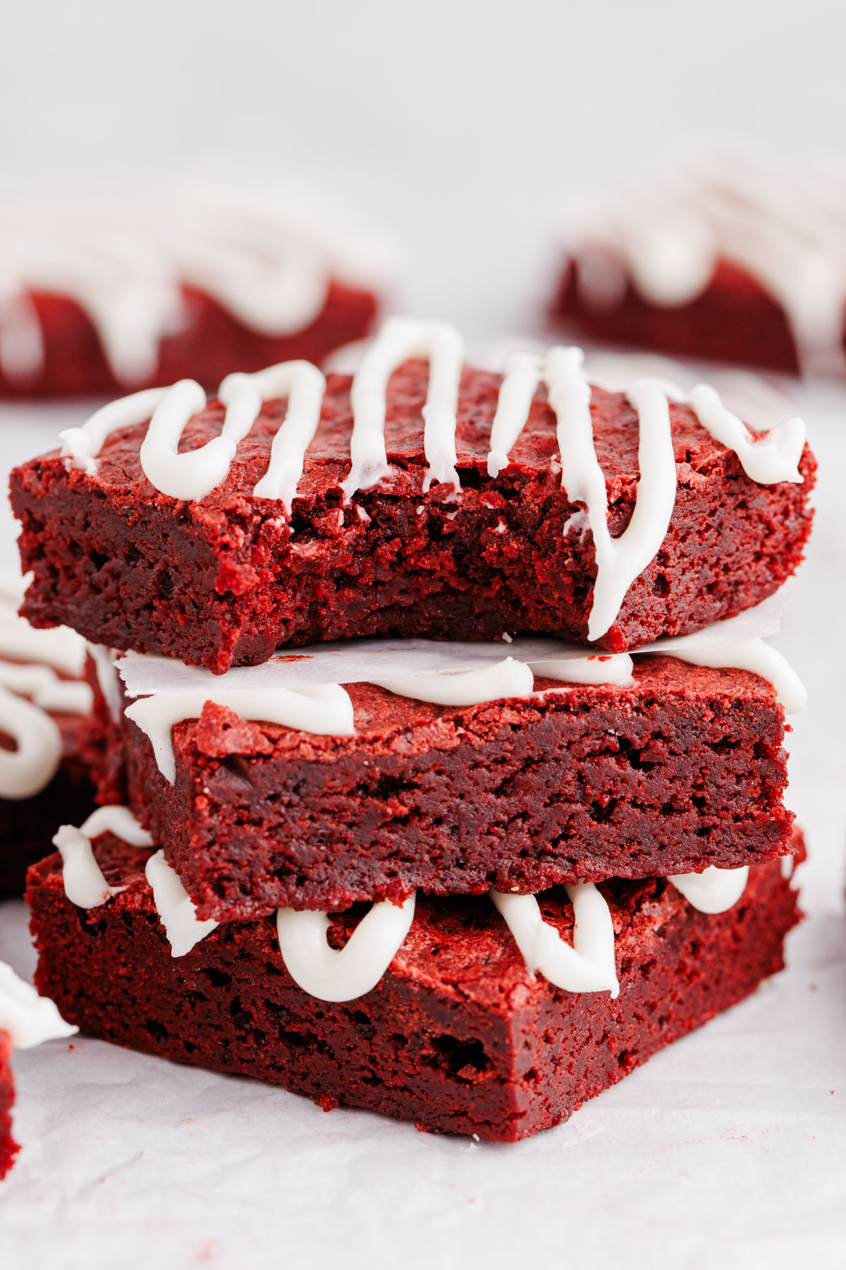 Red brownies stacked on top of one another with a bite taken out of the top brownie.