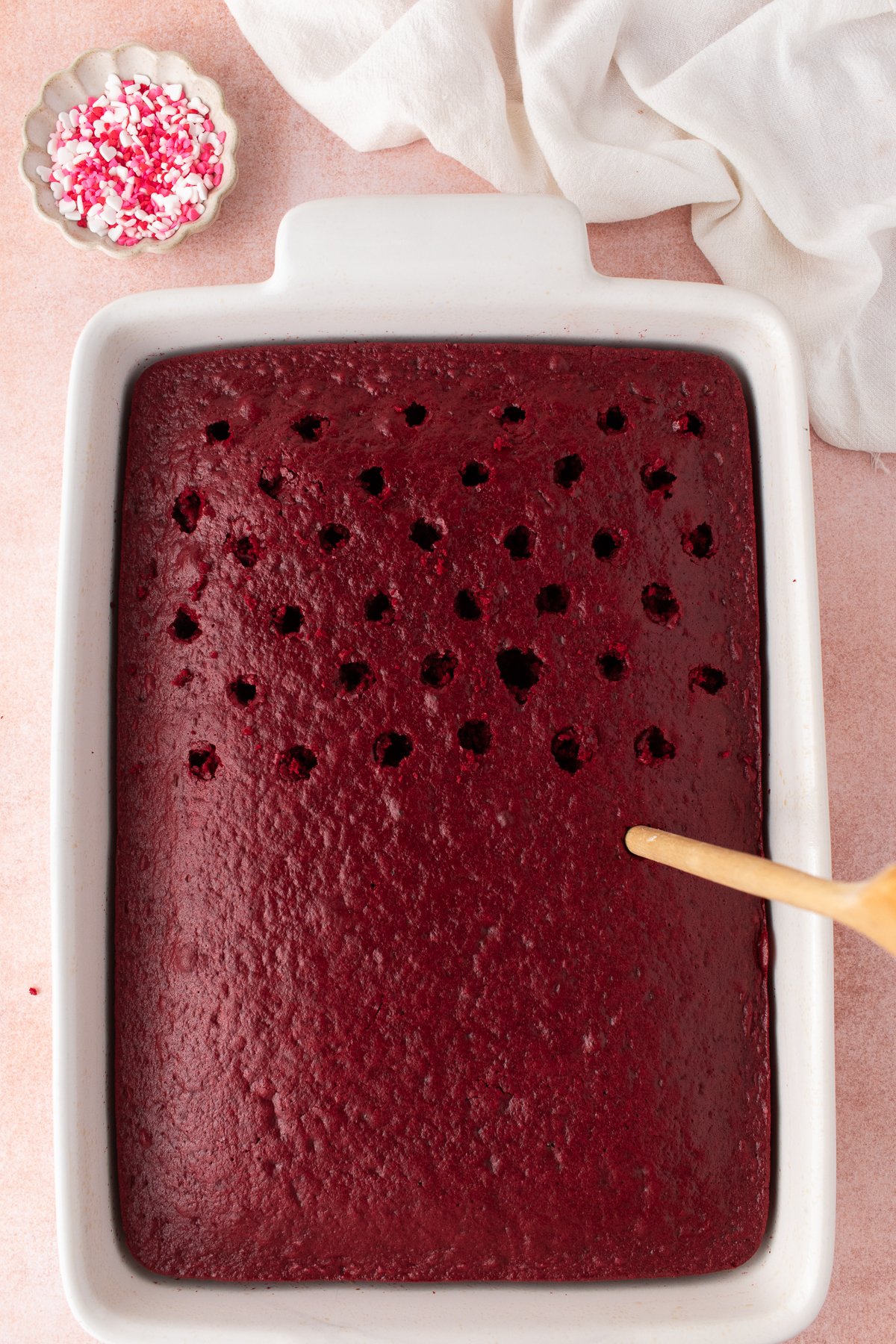 A wooden spoon poking holes in the cake.