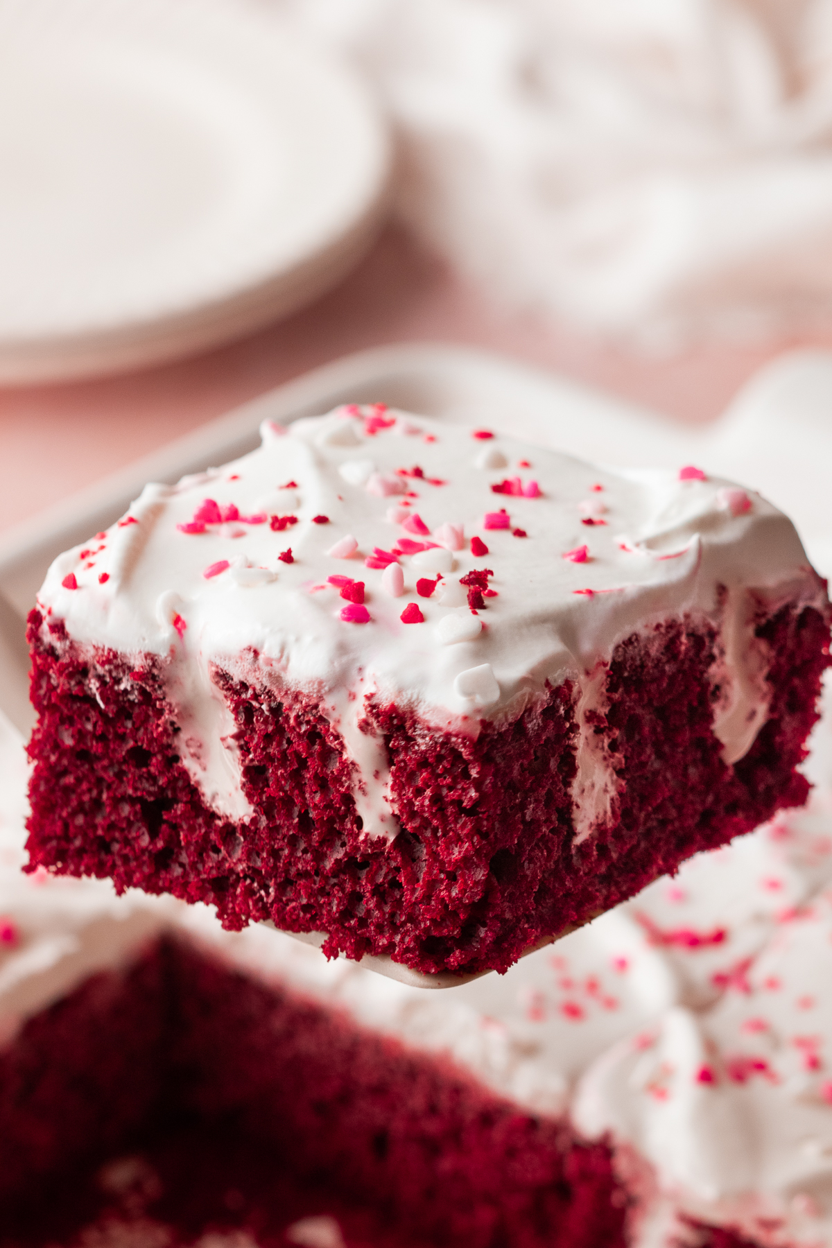 A slice of poke cake held up in the air.