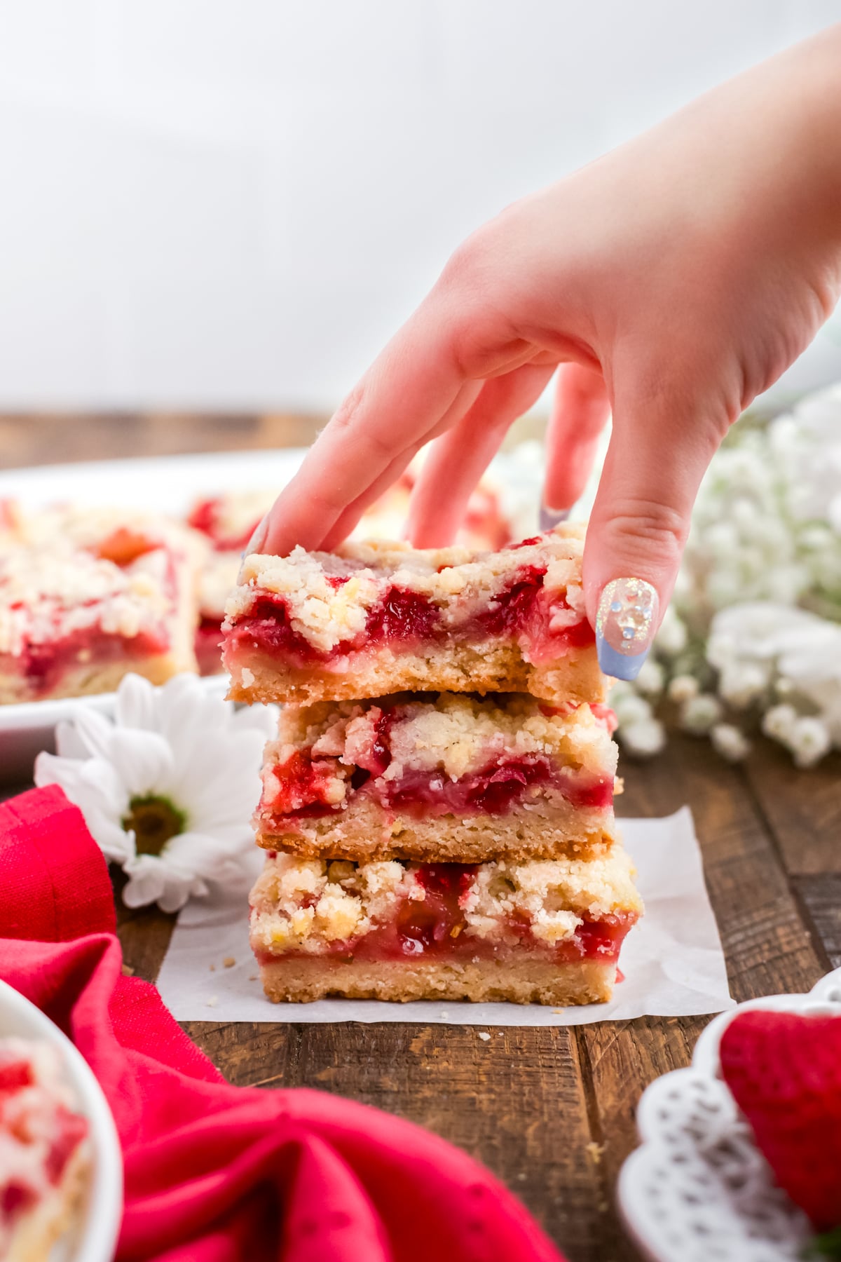 A hand taking a slice of strawberry bar off the stack.