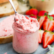 A jar full of Strawberry Butter qith a spoonful beiing lifted out