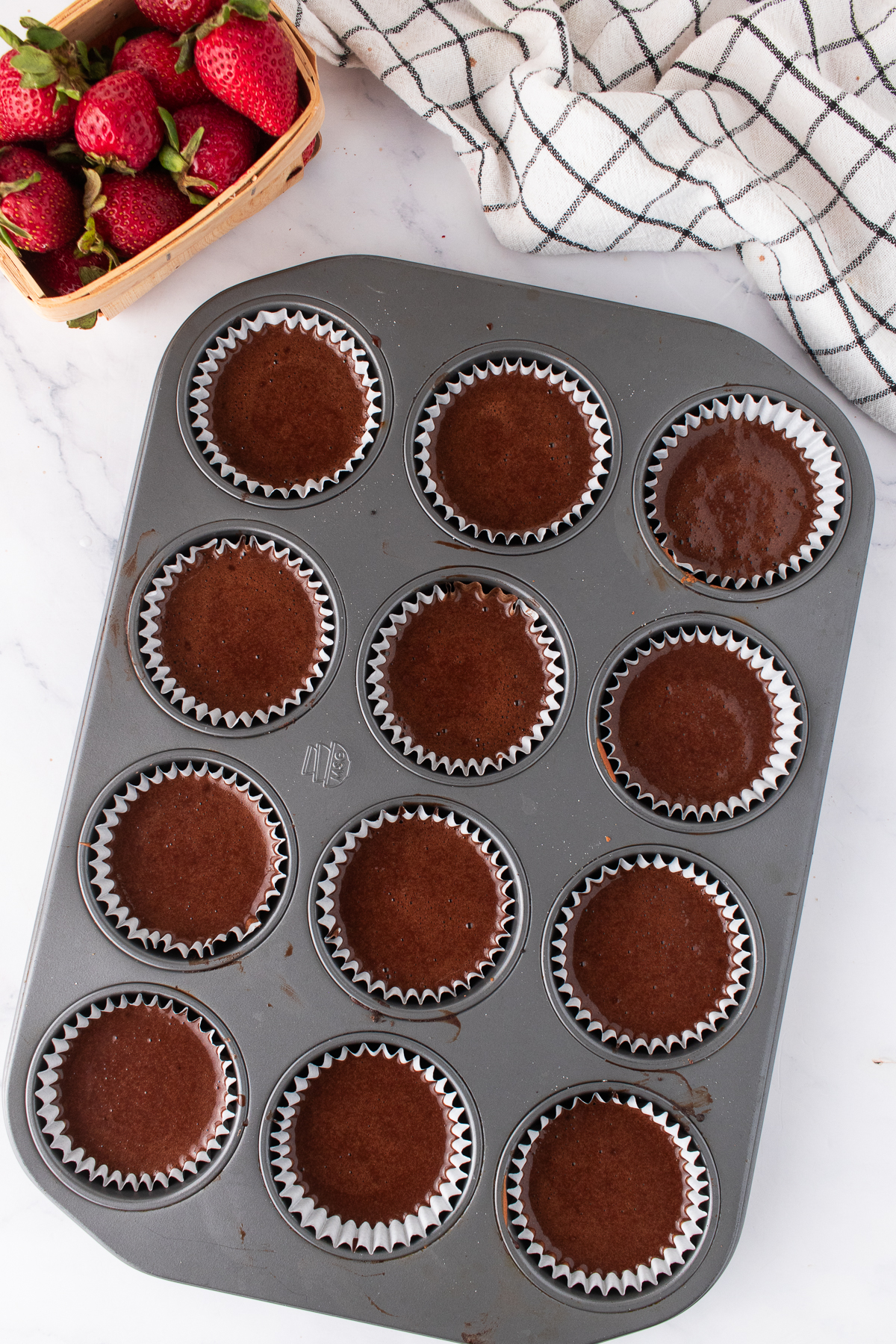 Liners filled with cupcake batter in a muffin tin.