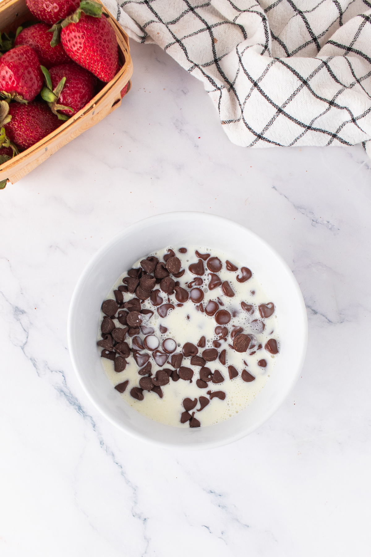 Heavy cream with chocolate chips melting in a bowl.