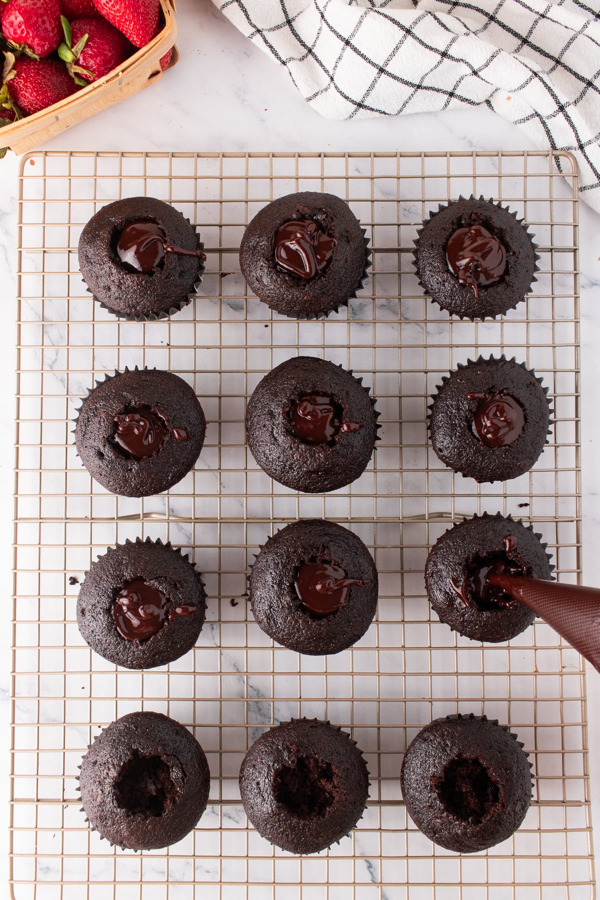 The center of the cupcake being removed and filled with ganache.