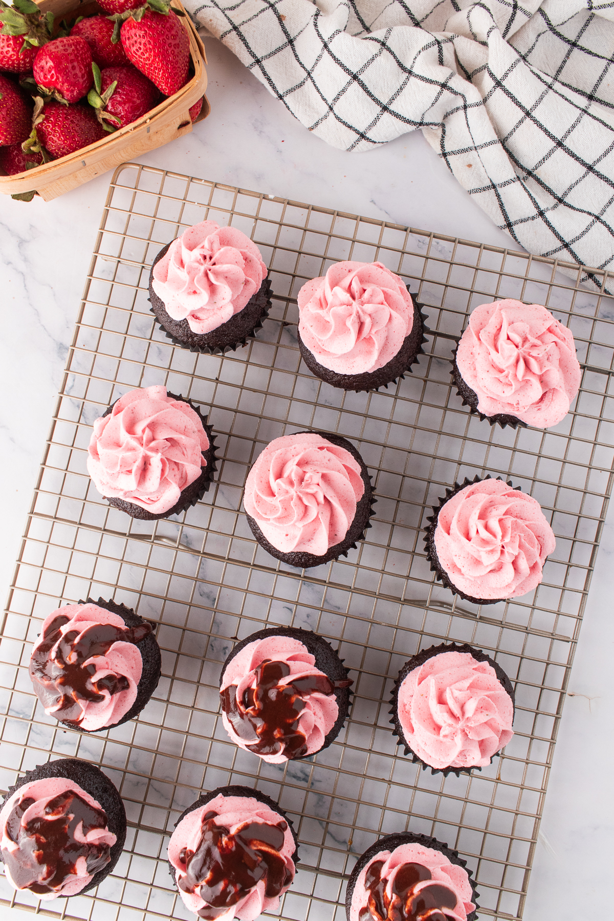 Strawberry buttercream piped and ganache drizzled onto the top of the cupcake.