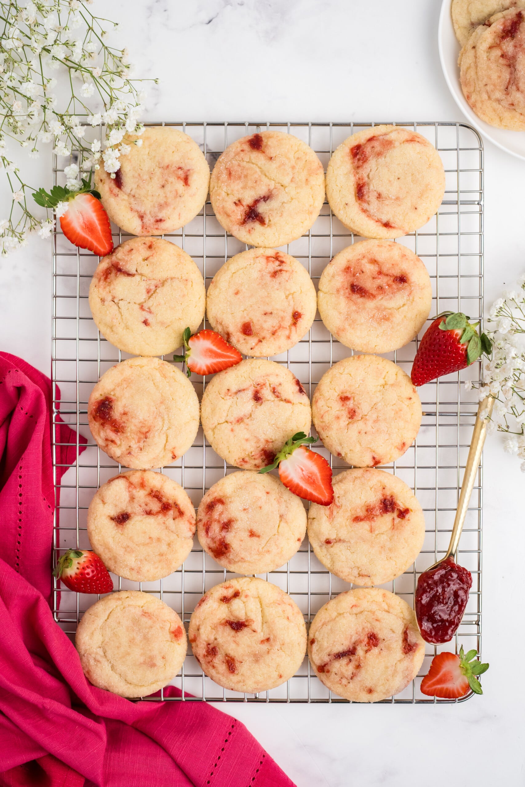Strawberry sugar cookies cooling on a baking rack.