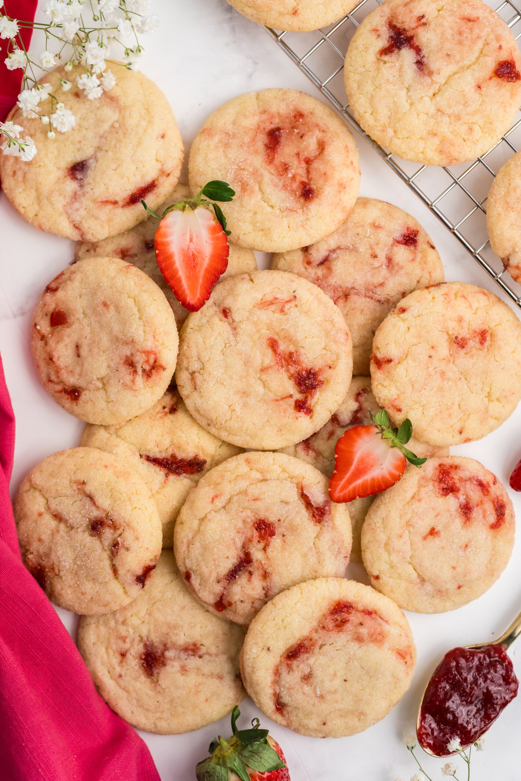 A pile of cookies with strawberry jam inside of them.