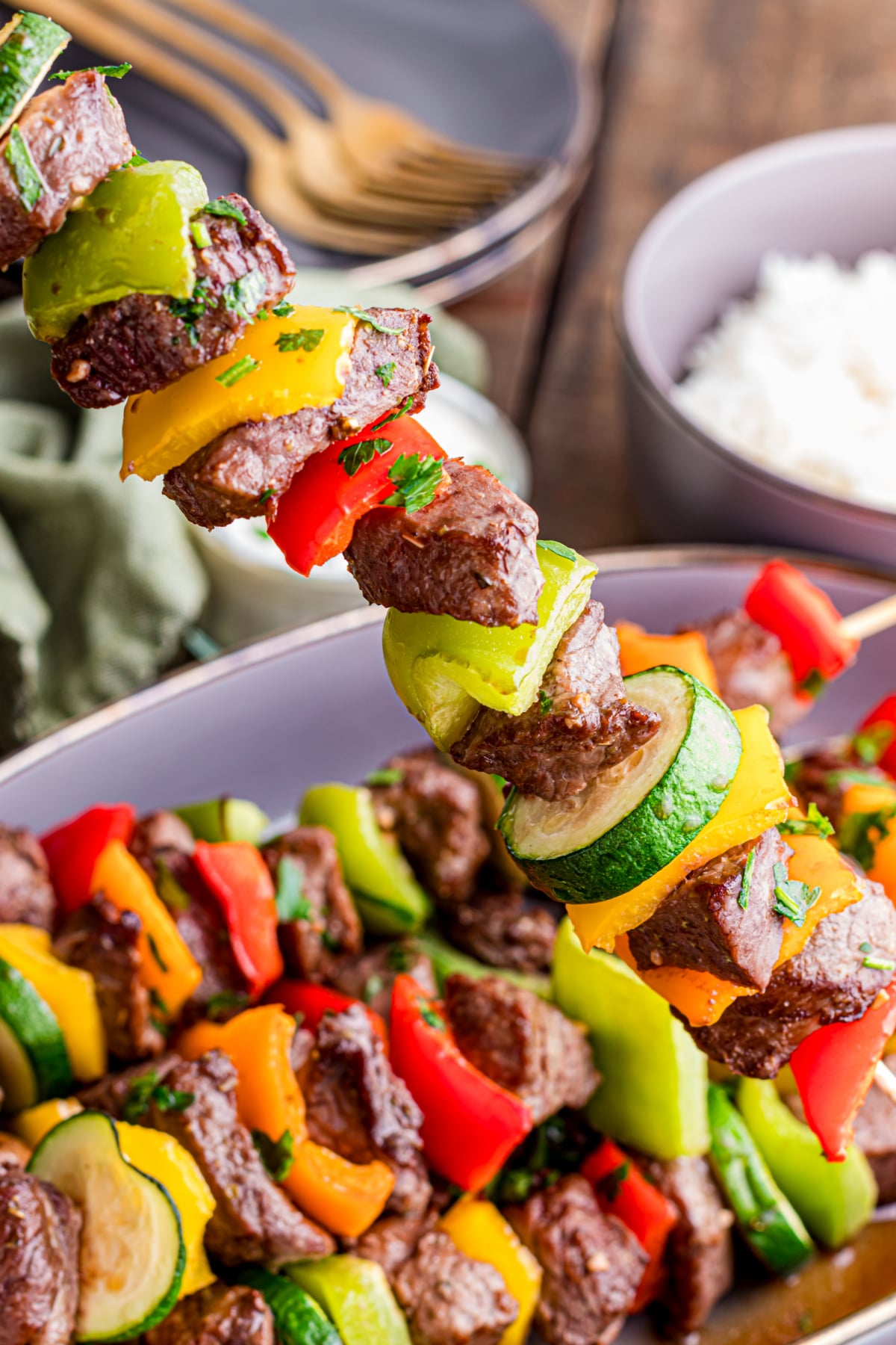 A skewer of beef kabobs being picked up.