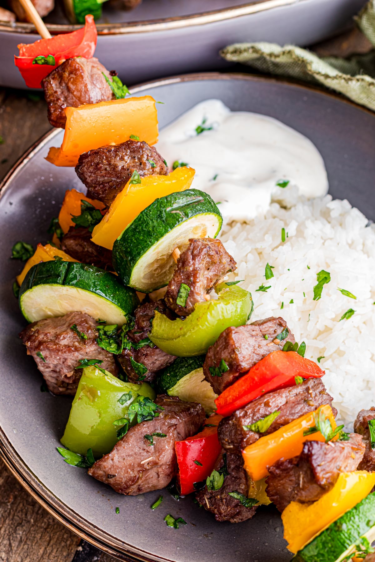 Beef kabobs in the oven with a side of rice on a plate.