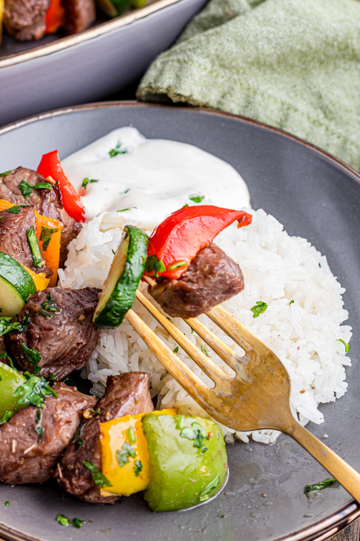 A fork picking up some beef, veggies over rice.