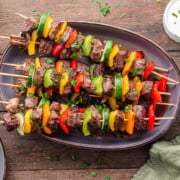 Beef kabobs in the oven served on a brown plate.