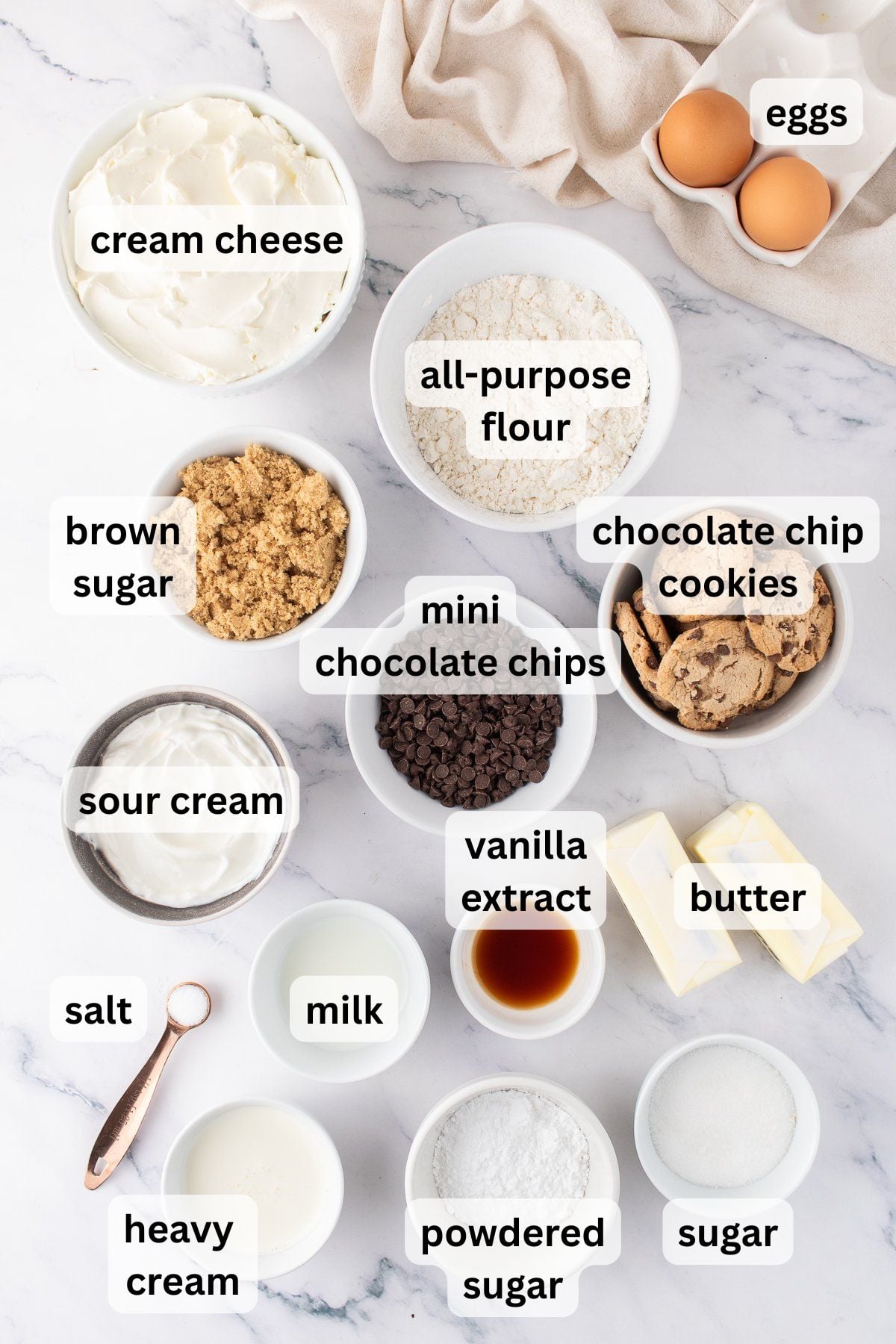 Ingredients to make this cheesecake with chocolate chip cookies on a table.