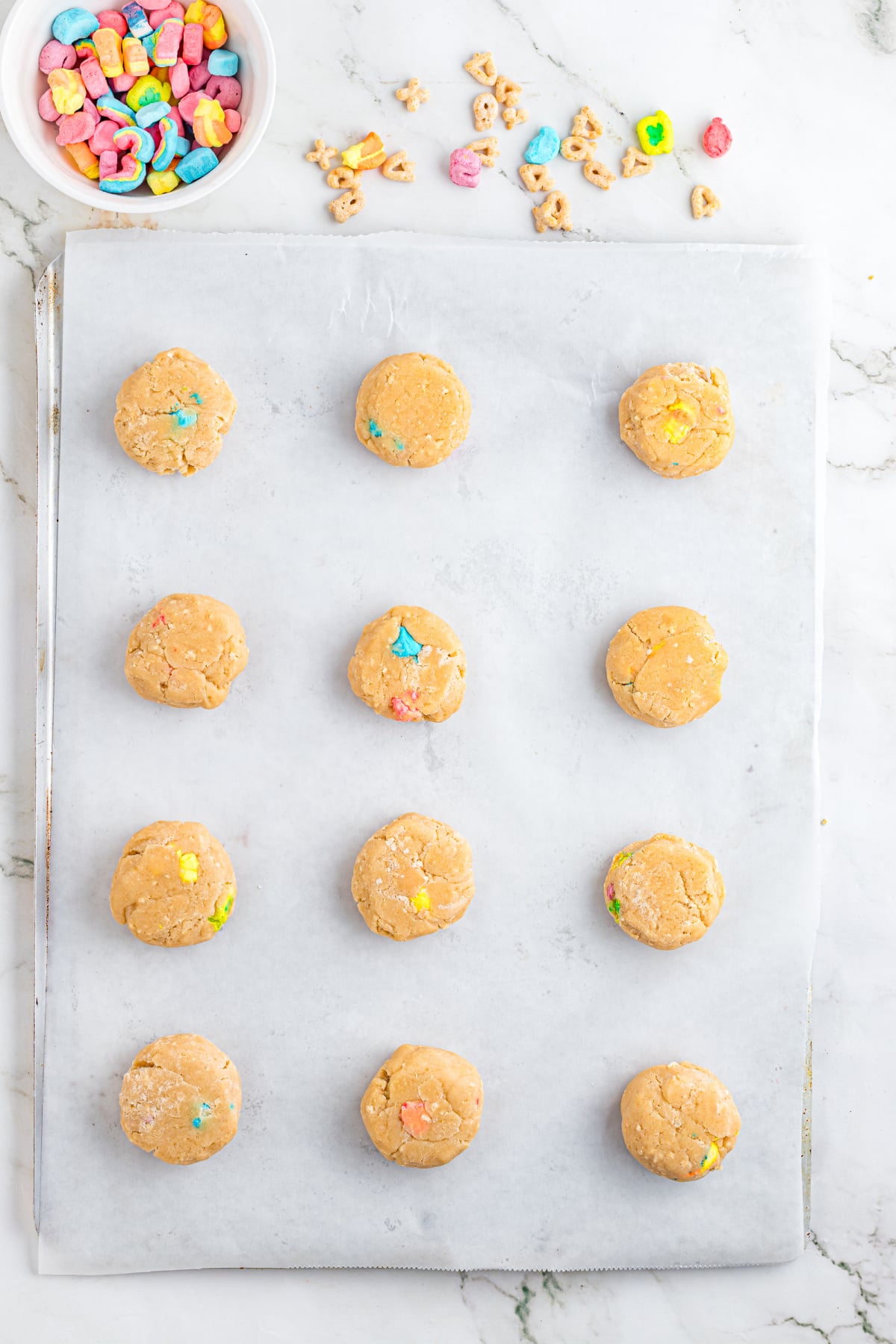 Cookie balls scooped onto parchment paper.