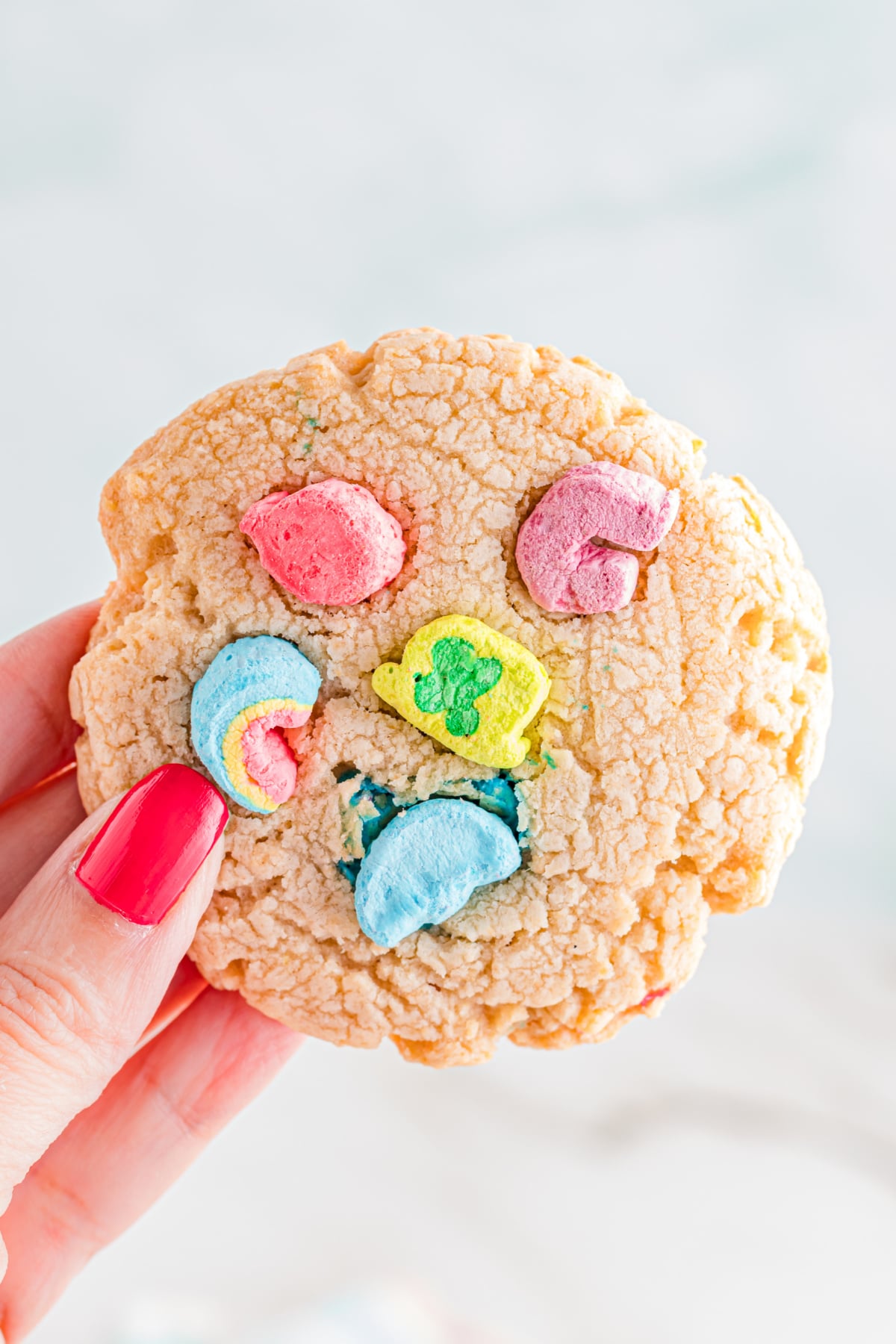 A cookie with marshmallows in it being held up in the air.