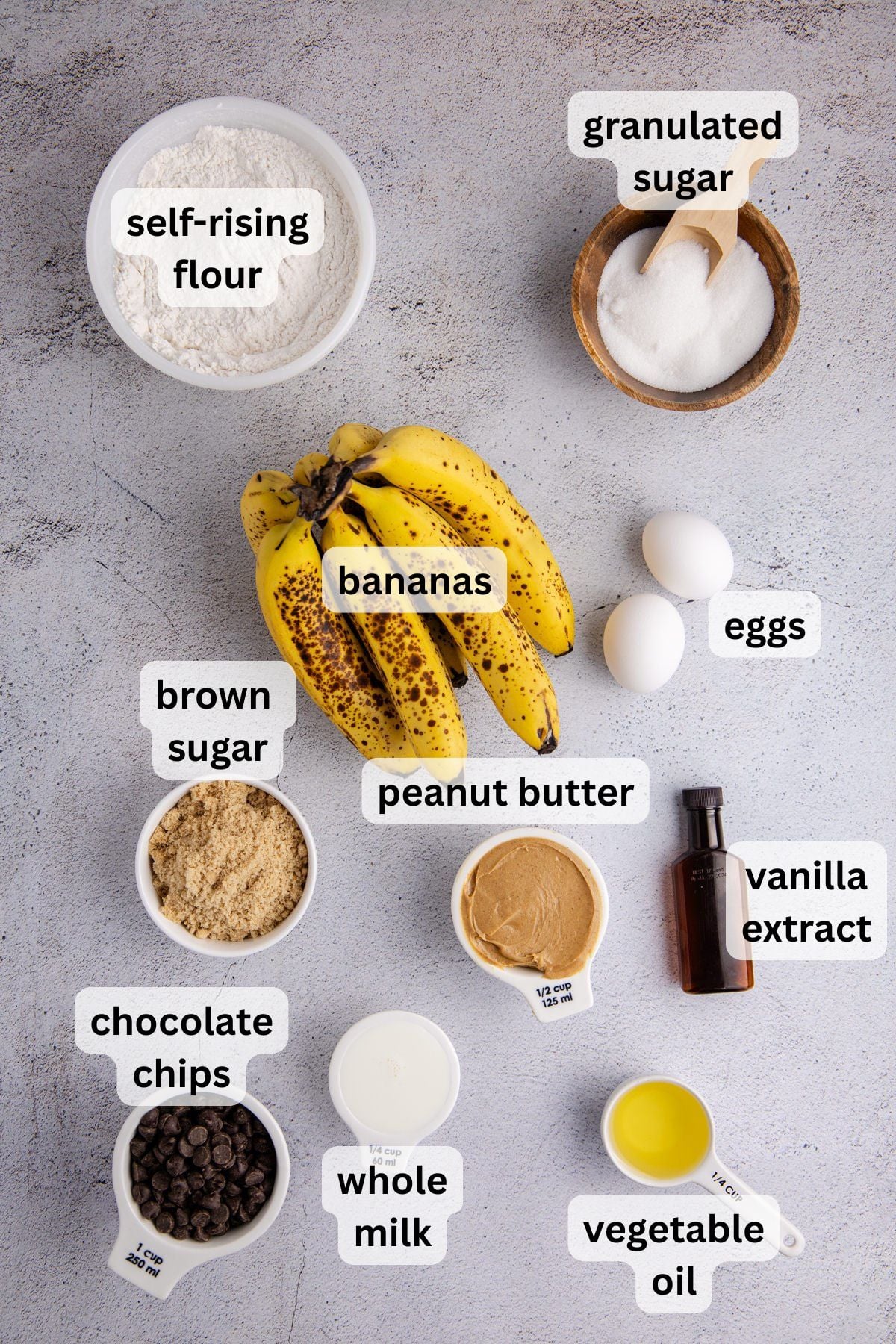 All of the ingredients needed to make peanut butter banana bread in bowls on a table.