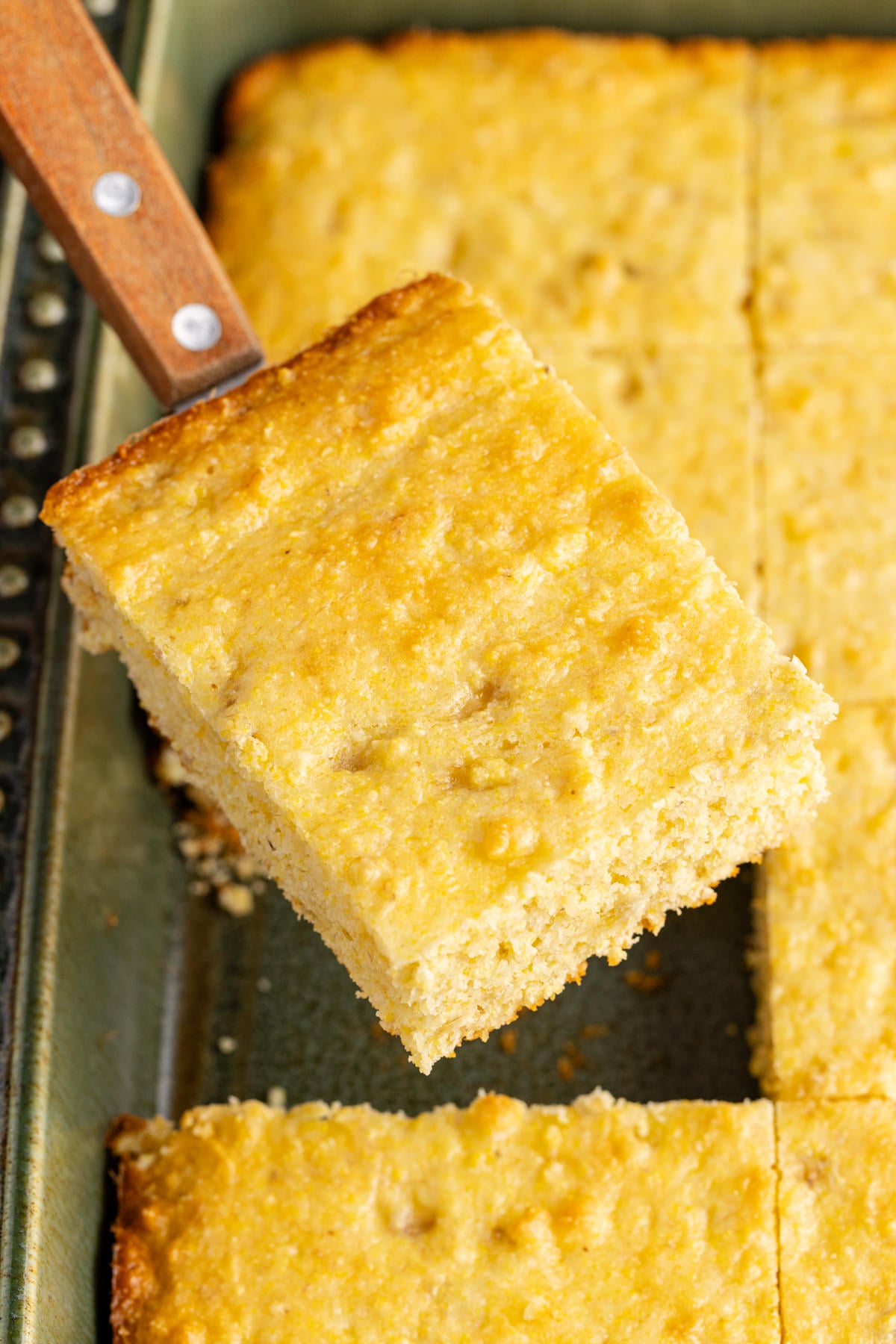 A slice of banana cornbread being held up in the air.