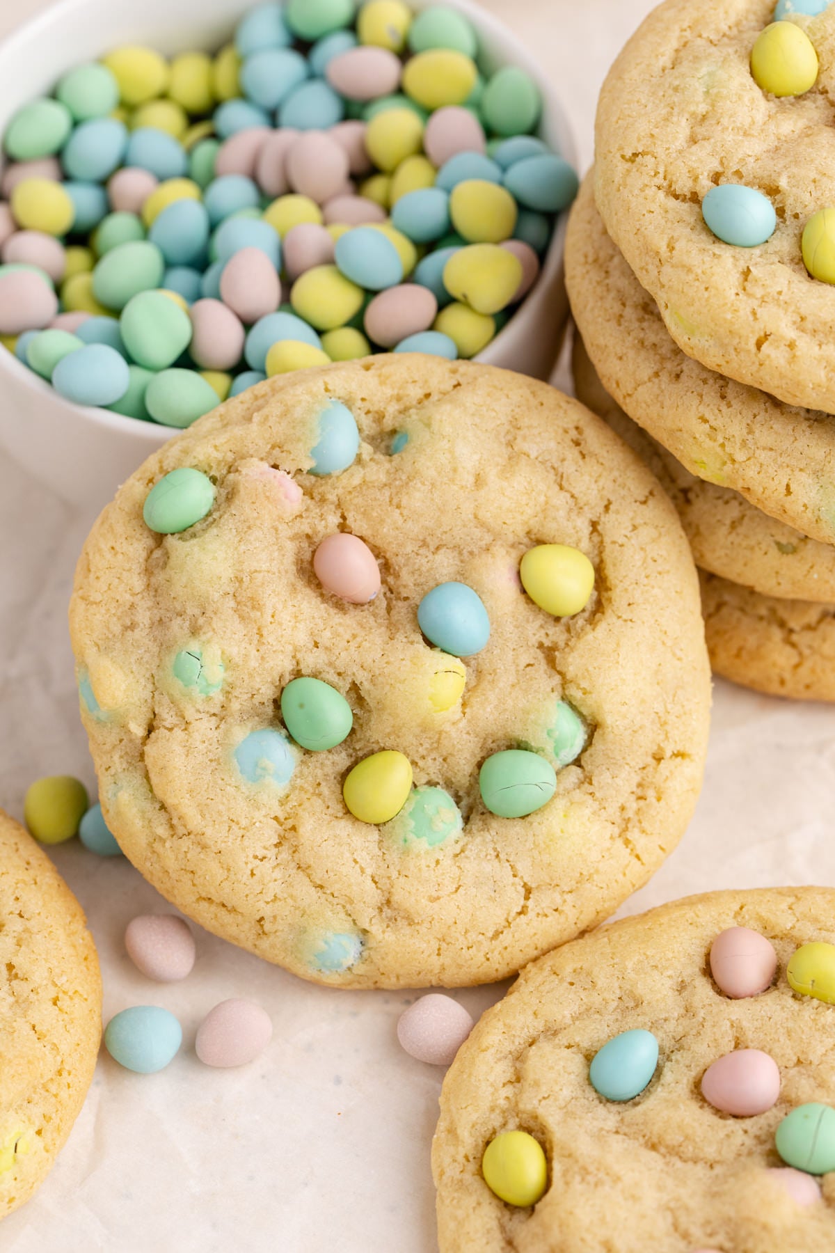 A cookie with mini eggs leaning on a bowl full of eggs.
