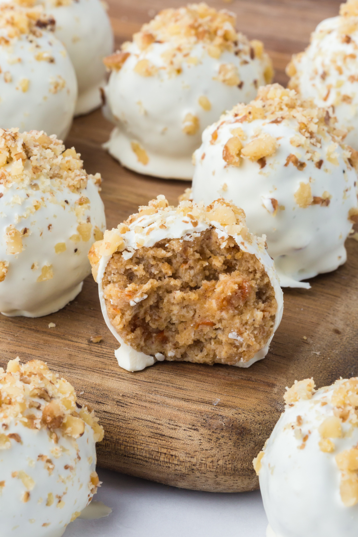 A truffle with carrot cake bitten on a wooden board.