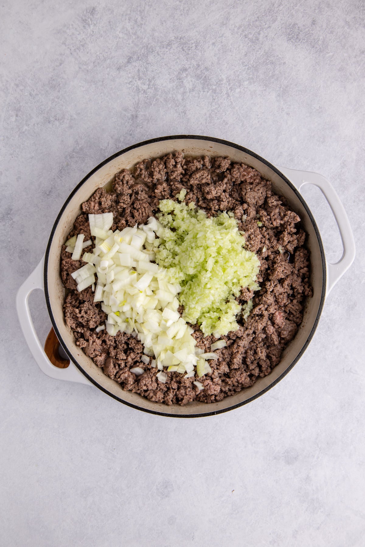 Ground beef with onion and celery in a skillet.