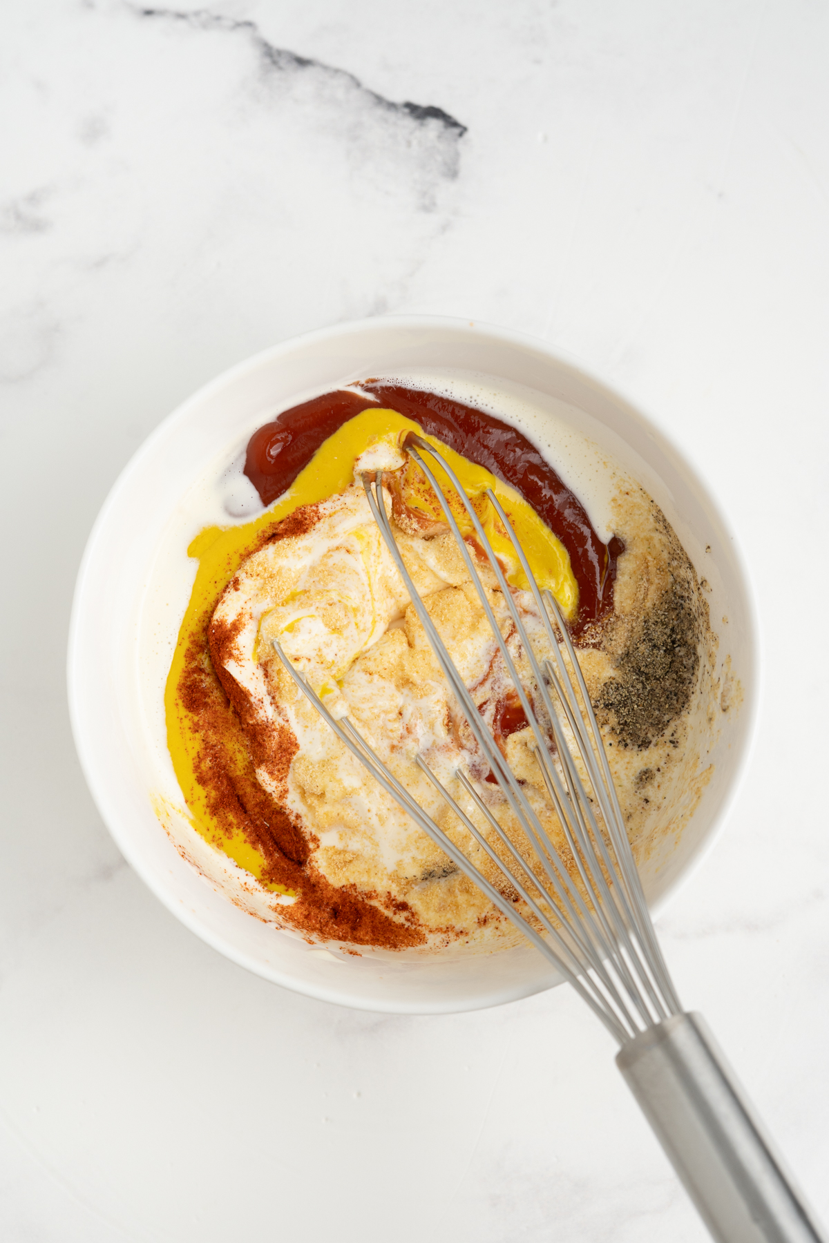 All of the necessary ingredients in a bowl with a whisk.