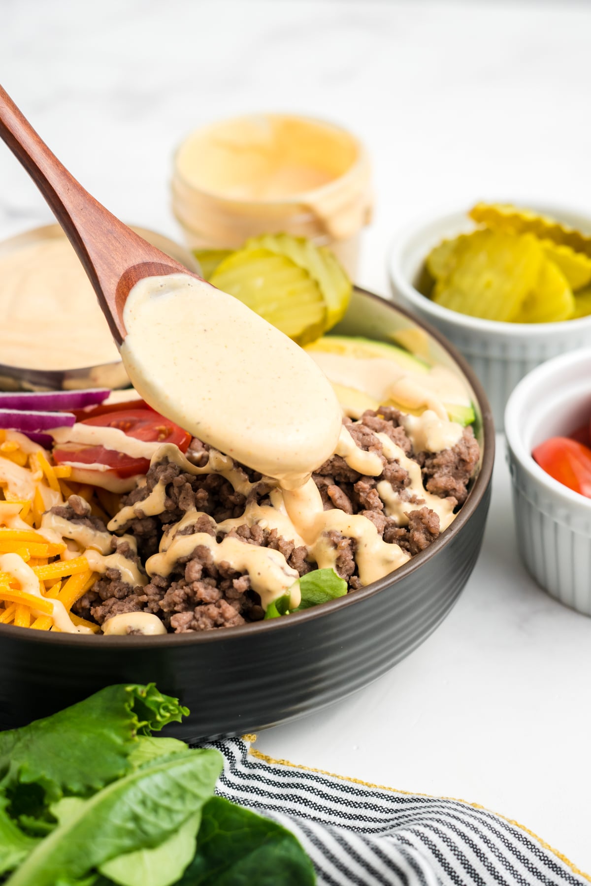 The Sauce in a full wooden spoon being lifted out of a bowlful.