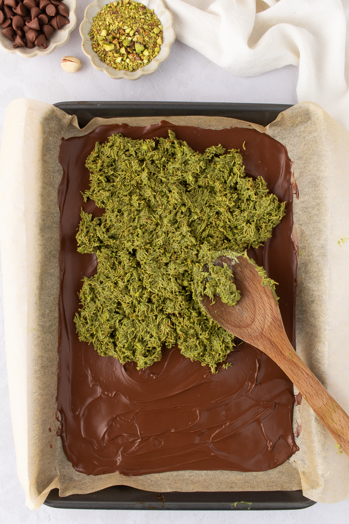 First layer of chocolate on parchment, on a baking sheet, being covered with kataifi layer.