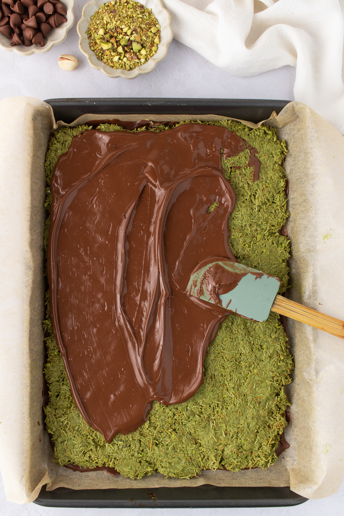 Top layer of melted chocolate being added to pressed kataifi layer.