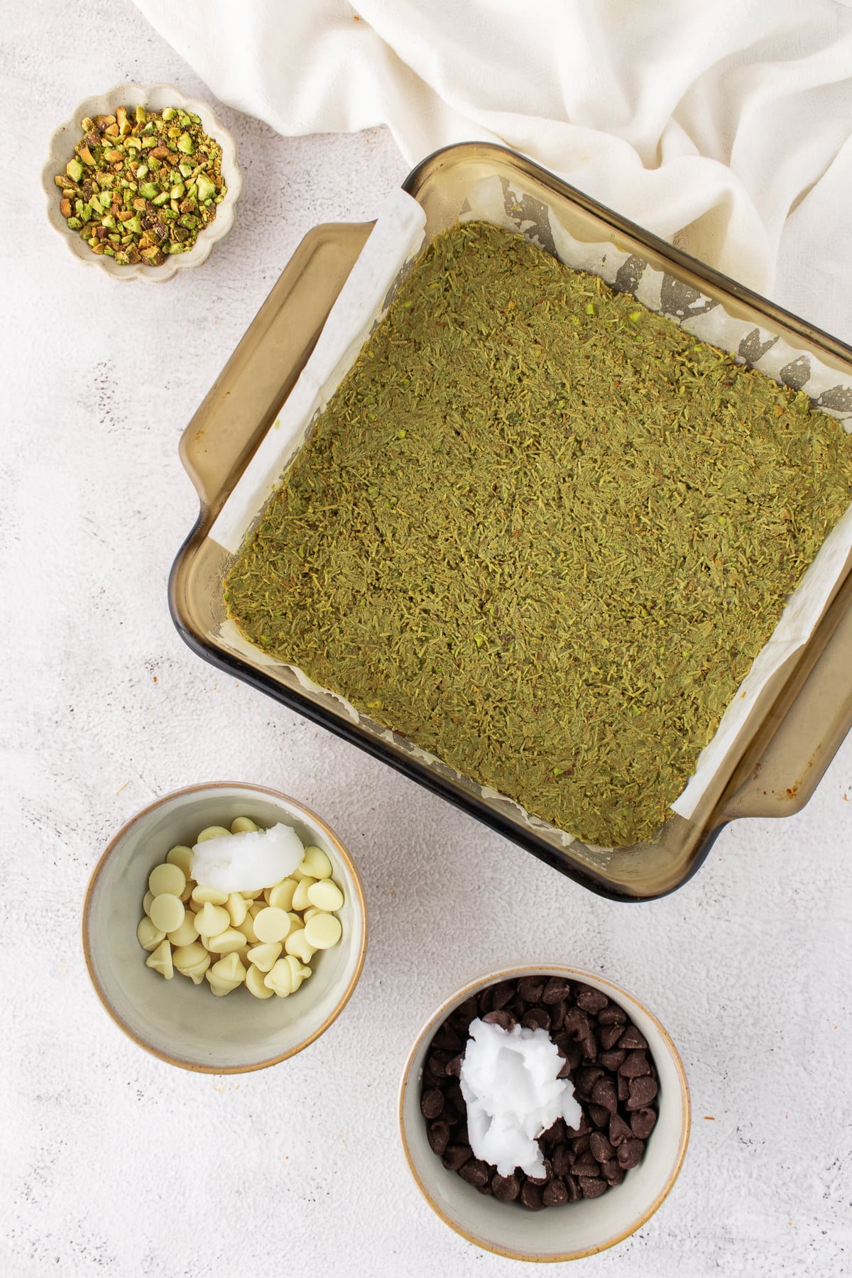 Melted white chocolate with the pistachio cream and chopped pistachios combined and spread over the brownie.