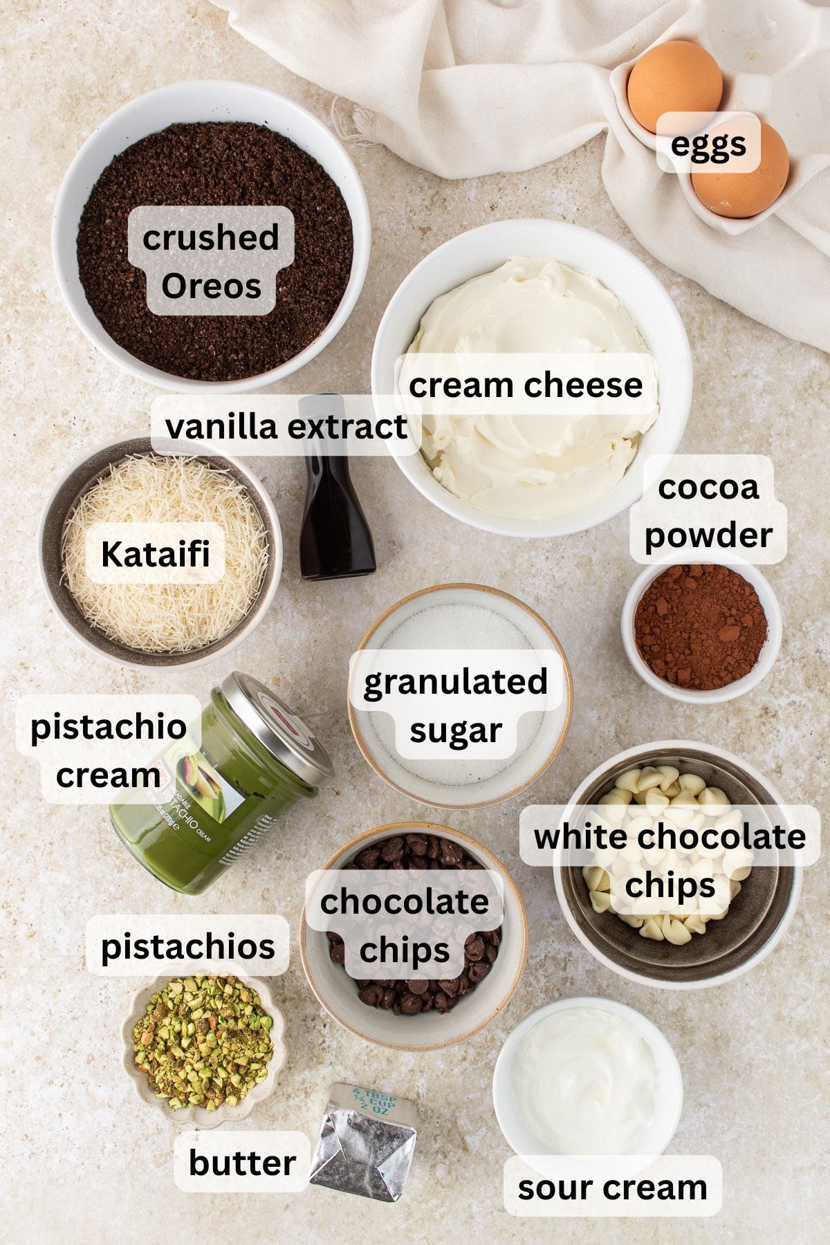 Ingredients to make these mini Dubai chocolate cheesecakes in bowls on a table.