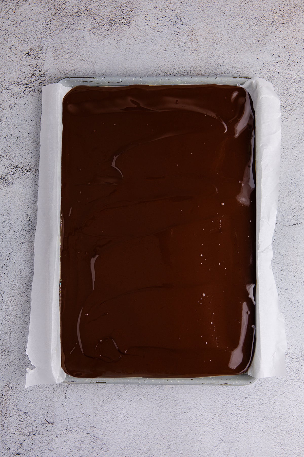 Melted chocolate spread evenly over the lined baking sheet