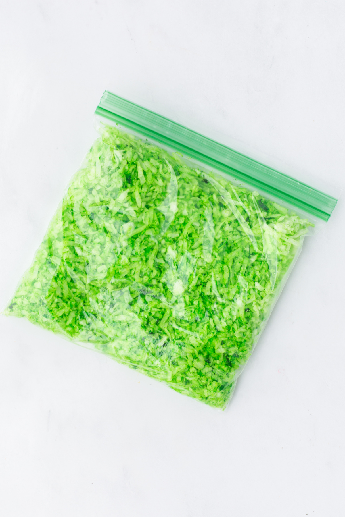 Shredded coconut with green food coloring in a small Ziploc bag.