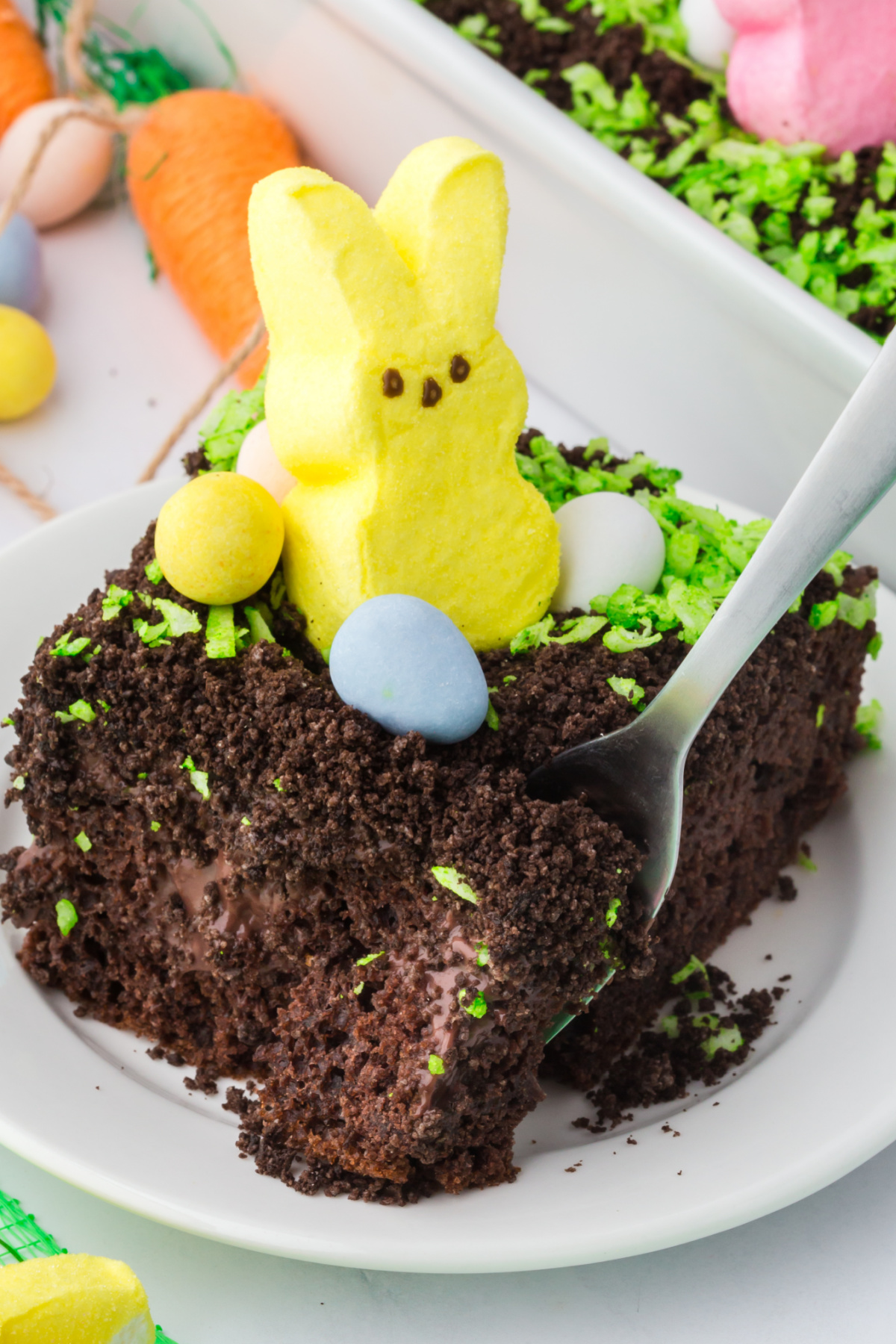 A slice of dirt cake with a peep on top with chocolate eggs.