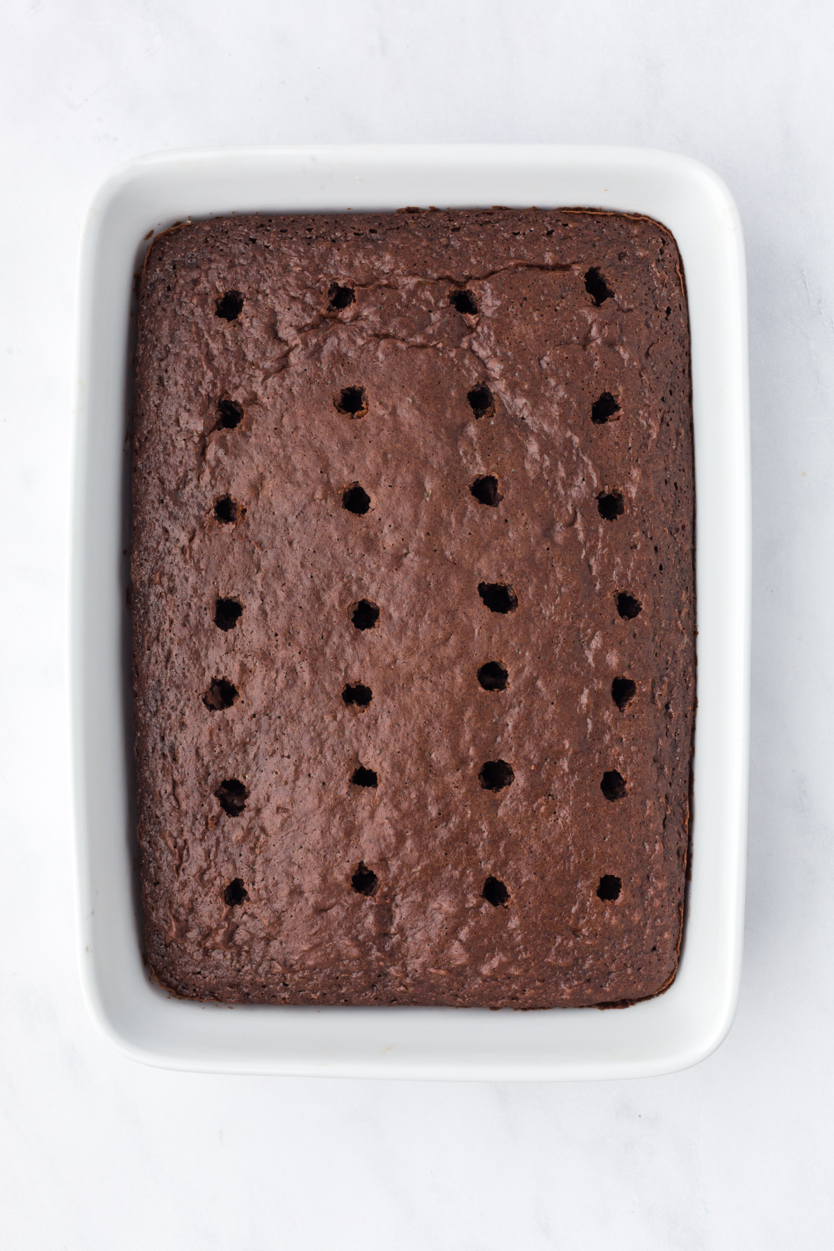 Holes poked into the baked cake with a wooden spoon.